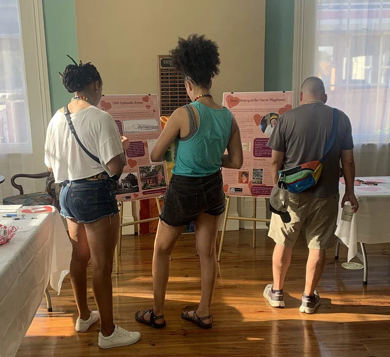 Three people from behind viewing informational display boards at an indoor event.