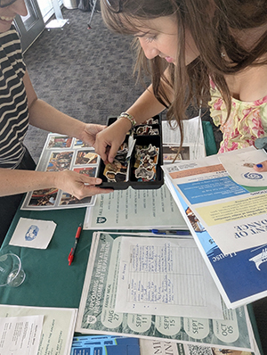 Student looks through sticker collection at the Art Department table at the Open House