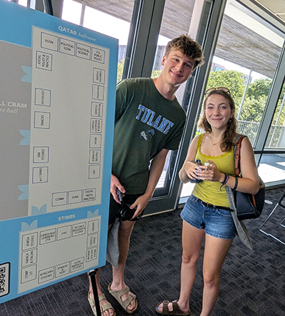 Students pose next to the Open House map poster board