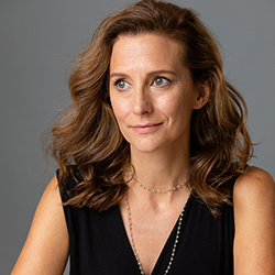Professional portrait of a thoughtful woman with brown hair and a gentle smile.
