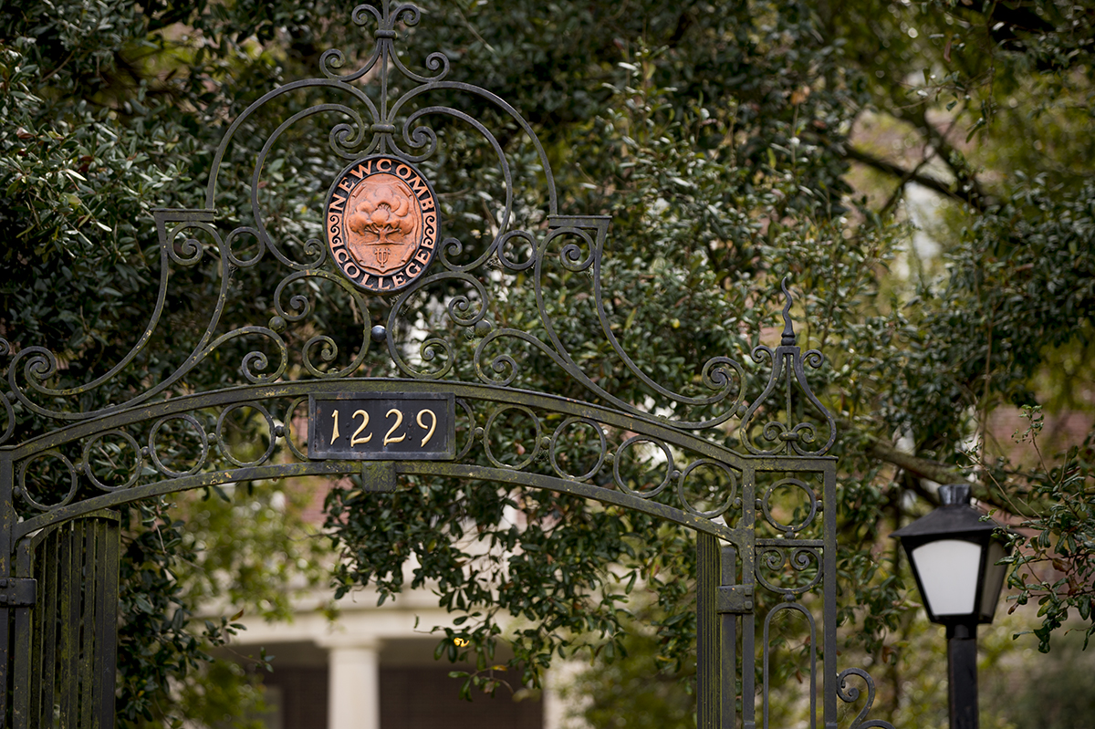 Ornate gate featuring the Newcomb College insignia, framed in oak tree limbs.
