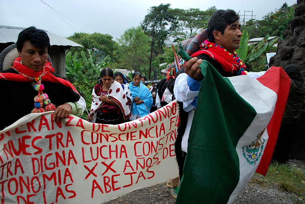 People in a procession carrying a banner with the names or those massacred
