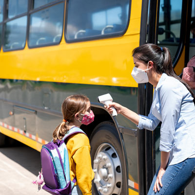 Kids getting on bus having their temperature taken