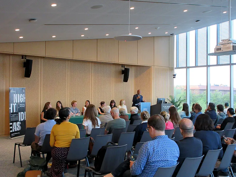 Panel discussion with speakers at a table addressing an audience in a bright conference room.