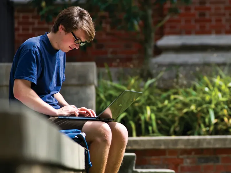 Tulane Student working on laptop outside in sunny weather